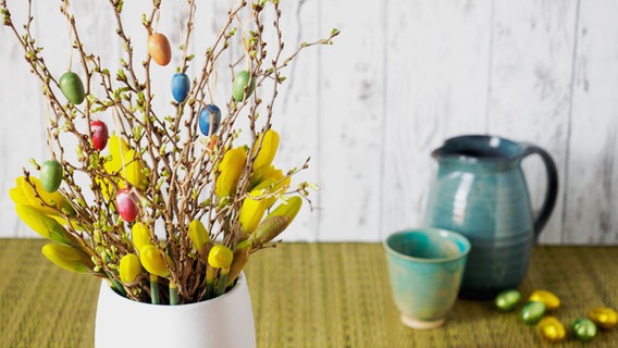 Zweige von einer Korkenzieher-Kirsche und Narzissen stehen in einer Vase auf einem Tisch. © NDR Foto: Anja Deuble