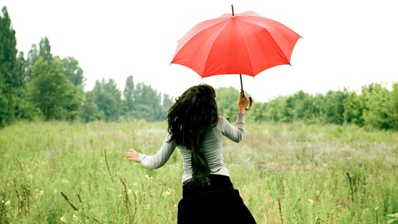 Eine junge Frau mit einem roten Regenschirm © photocase.de Foto: Maria Vaorin