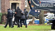 Nach der Razzia gegen "Reichsbürger" bringen Polizisten eine festgenommene Person in Karlsruhe aus einem Hubschrauber der Bundespolizei. © dpa Foto: Uli Deck
