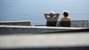 Ein Senionen-Paar sitzt an der Elbe auf einer Bank. © dpa Foto: Christian Charisius
