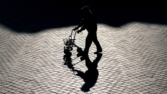 Ein älterer Mann geht im Gegenlicht mit einem Rollator © picture alliance / dpa Foto: Ralf Hirschberger