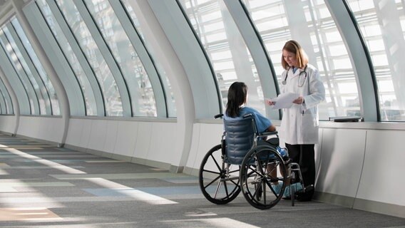 Eine Ärztin mit einer Frau im Rollstuhl  