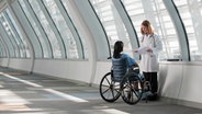 Eine Ärztin mit einer Frau im Rollstuhl  