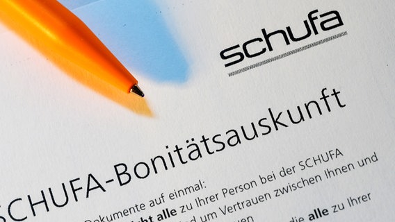 Ein orangefarbener Kugelschreiber liegt auf einem Formuliar der Schufa. © Picture Alliance Foto: Jens Niering