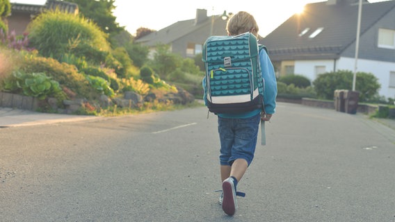 Ein Junge mit Schulranzen geht durch ein Wohnviertel. © photocase Foto: pip