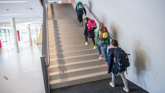 Schülerinnen und Schüler einer 4. Klasse gehen mit Abstand auf einer Treppe zu ihren Klassenräumen. © picture alliance / dpa Foto: Christian Charisius