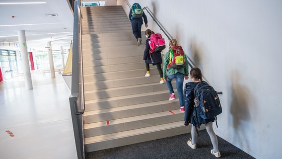 Schülerinnen und Schüler einer 4. Klasse gehen mit Abstand auf einer Treppe zu ihren Klassenräumen. © picture alliance / dpa Foto: Christian Charisius