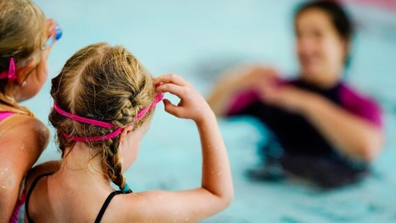 zwei Mädchen nehmen im Schwimmbad an einem Anfängerschwimmkurs für Kinder teil. © picture alliance/dpa/Uwe Anspach Foto: Uwe Anspach