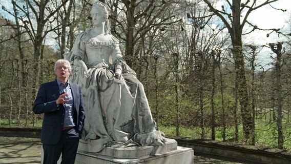 Historiker Dr. Tillmann Bendikowski steht neben einem Denkmal von Königin Marie © NDR 
