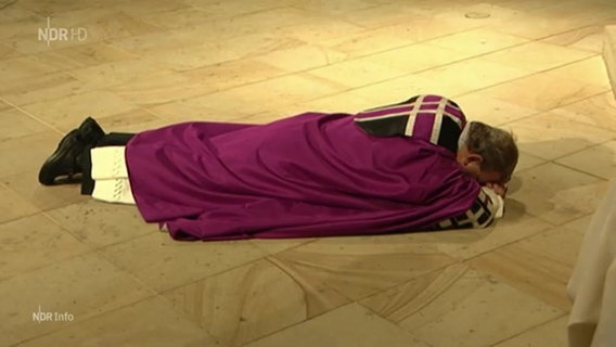 Bischof Bode liegt in der Kirche mit dem Bauch auf dem Boden. © screenshot 