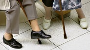 Füße zweier älterer Damen mit Stöcken, die sich sitzend unterhalten. © photocase Foto: willma..