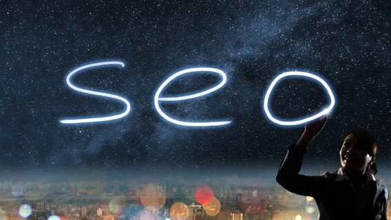Eine Frau "zeichnet" mit Licht die Buchstaben "SEO" in den Nachthimmel. © Panther Media Foto:  elwynn