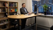 Harro Hallmann steht an einem höhenverstellbaren Schreibtisch und arbeitet am Computer. © Karin Riggelsen Foto: Karin Riggelsen