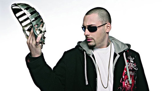 Der Rapper Sido schaut auf die Maske in seiner Hand. © Universal Music Foto: Florian Wörner