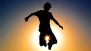 Bild einer jungen Person, die vor der Sonne in die Höhe springt © guirmoro / photocase.de Foto: guirmoro