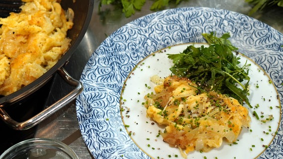 Käsespätzle mit Rucola-Kräutersalat auf einem Teller serviert. © NDR Foto: Florian Kruck