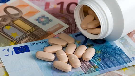 Tabletten fallen aus einer Dose auf Euroscheine. © Fotolia.com Foto: Stefan Redel