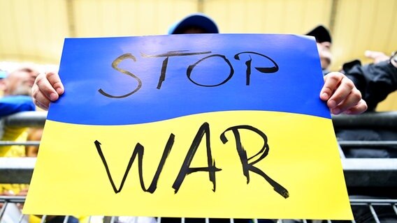 Ein Zuschauer hält ein Schild in den ukrainischen Landesfarben und der Aufschrift "Stop War" in die Höhe. © WITTERS Foto: TimGroothuis