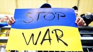 Ein Zuschauer hält ein Schild in den ukrainischen Landesfarben und der Aufschrift "Stop War" in die Höhe. © WITTERS Foto: TimGroothuis
