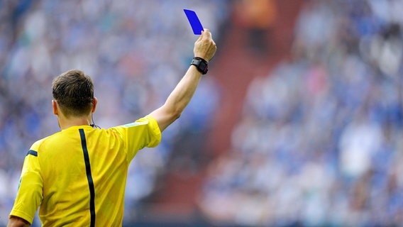 Ein Schiedsrichter zeigt eine blaue Karte. © IMAGO / Kolvenbach 