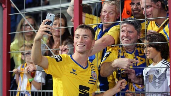 Braunschweigs Yari Otto macht Selfies mit den Eintracht-Fans. © imago/Hübner 