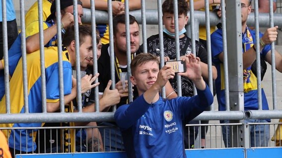 Braunschweigs Luc Ihorst macht ein Selfie mit Eintracht-Fans © IMAGO / regios24 