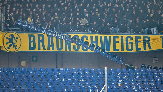 Fans aus Braunschweig werfen eine ganze Sitzreihe im Satdion von Hannover 96 von der Tribüne. © IMAGO / osnapix 