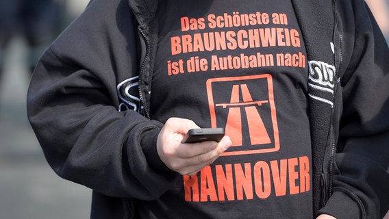 Ein Mann trägt ein T-Shirt mit der Aufschrift: "Das schönste an Braunschwei ist die Autobahn nach Hannover. © picture alliance / dpa Foto: Alexander Körner