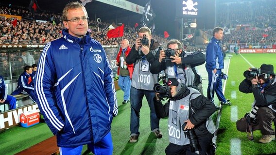 Schalkes Trainer Ralf Rangnick steht am Spielfeldrand und ist von Fotografen umringt. © dpa 