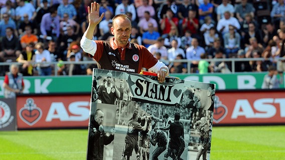 St. Paulis Trainer Holger Stanislawski trägt ein Bild vom Spielfeld. © dpa 