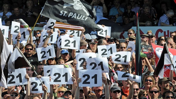 St. Paulis Fans halten Zettel mit der Nummer 21 hoch, der Trikotnummer von Trainer Holger Stanislawski. © dpa 