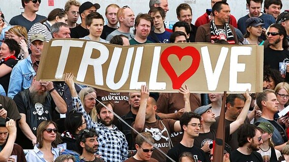 St. Paulis Fans halten Plakat für Co-Trainer Andre Trulsen hoch. © dpa 
