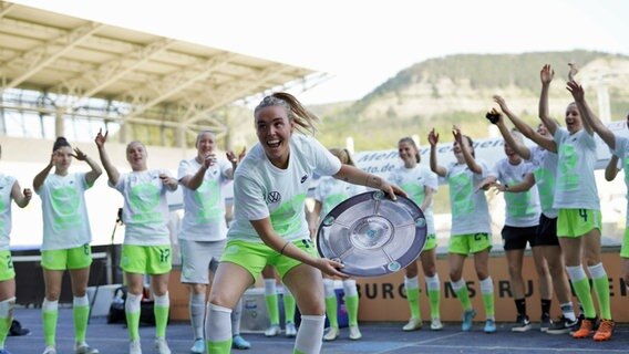 Wolfsburgs Jill Roord (v.) bejubelt mit einer Meisterschale aus Pappe und ihren Mitspielerinnen in Stadion in Jena den vorzeitigen Gewinn des siebten deutschen Meistertitels. © IMAGO / Sports Press Photo 