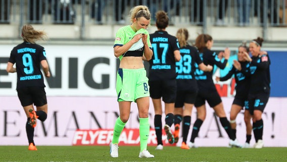 Wolfsburgs Lena Lattwein ist frustriert, während Hoffenheims Spielerinnen einen Treffer bejubeln. © IMAGO / regios24 
