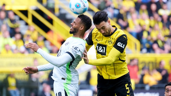 Wolfsburgs Lukas Nmecha (l.) und Dortmunds Remy Bensebaini kämpfen um den Ball. © picture alliance/dpa | Bernd Thissen 