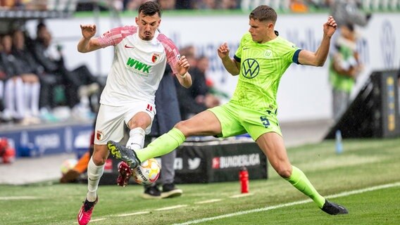 Wolfsburgs Micky van de Ven (r.) und Augsburgs Mergim Berisha kämpfen um den Ball. © picture alliance/dpa | David Inderlied 