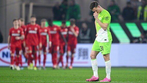 Wolfsburgs Yannick Gerhardt ist enttäuscht, während im Hintergrund Stuttgarter Spieler einen Treffer bejubeln. © IMAGO / RHR-Foto 