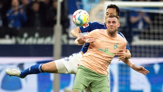 Bremens Marvin Ducksch (vorne) und Schalkes Maya Yoshida kämpfen um den Ball. © picture alliance/dpa | Bernd Thissen 