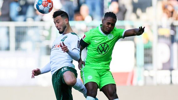 Wolfsburgs Ridle Baku (r.) und Gladbachs Ramy Bensebaini kämpfen um den Ball. © IMAGO / Jan Huebner 