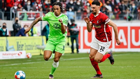 Wolfsburgs Kevin Mbabu (l.) und Freiburgs Vincenzo Grifo kämpfen um den Ball. © IMAGO / Eibner 