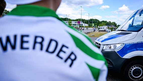 Ein Bremen-Fan steht vor einem Polizeifahrzeug. © IMAGO / Nordphoto 