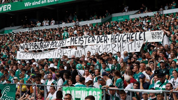 Werder-Fas zeigen ein Spruchband gegen die Polizei Wolfsburg. © IMAGO / Joachim Sielski 