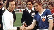 Franz Beckenbauer (l.) und Bernd Bransch schütteln sich vor dem Anpfiff der WM-Partie BR Deutschland - DDR die Hände. © IMAGO / WEREK 
