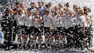 Die deutsche Mannschaft mit Maren Meinert, die den Pokal in die Luft hält, jubelt ausgelassen im Konfetti-Regen. © picture alliance / dpa Foto: Tobias Heyer