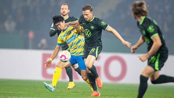 Wolfsburgs Yannick Gerhardt (r.) und Braunschweigs Keita Endo kämpfen um den Ball. © picture alliance/dpa | Swen Pförtner 