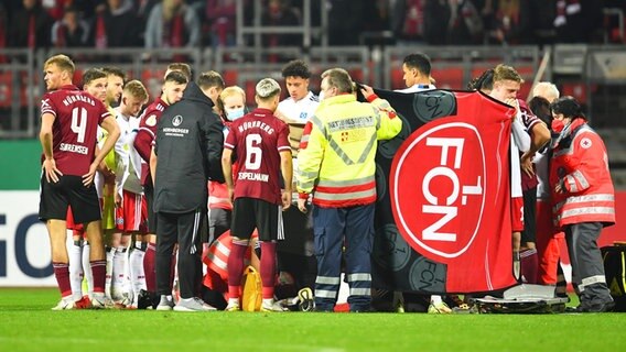 Spieler von Hamburg und Nürnberg bilden einen Sichtschutz um den verletzten Nürnberger Tom Krauß, der behandelt wird. © IMAGO / Zink 