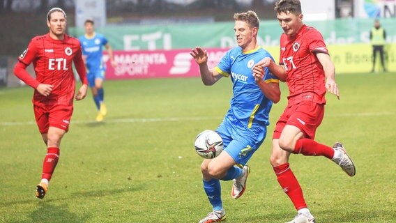 Braunschweigs Danilo Wiebe (M.) und Kölns Christoph Greger kämpfen um den Ball. © IMAGO / Eibner 
