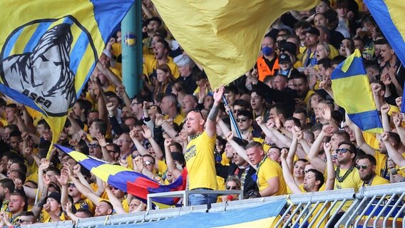 Braunschweigs Fans jubeln ihrer Mannschaft von der Tribüne aus zu. © IMAGO / Hübner 