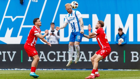 Rostocks Nils Fröling (M.) kämpft gegen Axel Borgmann (l.) und Niko Bretschneider von Energie Cottbus um den Ball. © IMAGO / Andy Bünning 