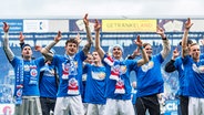 Rostocks Spieler bejubeln den Aufstieg mit den Fans. © IMAGO / Fotostand 